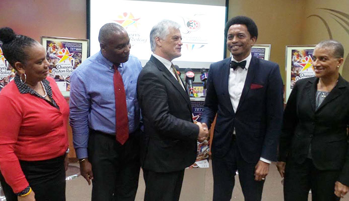 Australian High Commissioner to T&T, John Pilbeam,left, TTOC President Brian Lewis put on their Queen Baton Relay hand bands during the launch of the relay at Olympic House on Abercromby Street, Port-of-Spain yesterday. The Queen's baton will arrives in Trinidad on Sunday