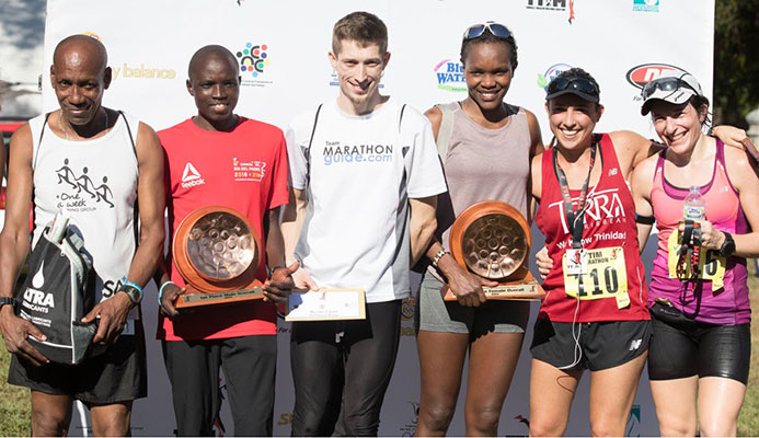 Kenya’s Grace Kahura crosses the finishline in 2:53.50, to place first among the women and third overall, during the TT International Marathon at the Queen’s Park Savannah West, Port of Spain,yesterday. At right, Minister of Sport and Youth Affairs Shamfa Cudjoe holds the finish line banner.