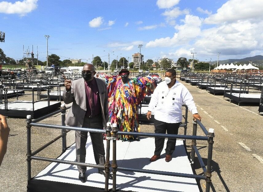 REBRANDED CITY: National Carnival Commission (NCC) chairman Winston “Gypsy” Peters, left, and NCC Commi Marcelle are joined by a Pierrot Grenade as they took members of the media on a tour of the Carnival pods at the Q Rebranded Carnival City in Port of Spain yesterday. Construction works are ongoing on the stage area and on the C groups of vaccinated patrons will be accommodated during Carnival events to be staged at the venue. —Photo: JER CRUICKSHANK