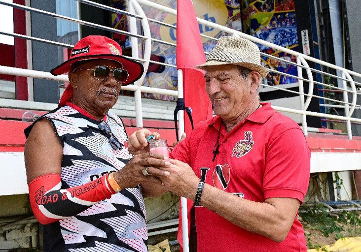 HONOURING JUMBO: Sports super fans Joey “Porche” Richardson, left, and Sam Salloum of the Trini Posse Stand light a candle yesterday to remember fellow sports fan Keith Martin, better known as “Jumbo, the nutsman”, at the Queen’s Park Oval, Port of Spain, during the second day of the West Indies Championship fifth-round match.  —Photo: JERMAINE CRUICKSHANK (Image obtained at trinidadexpress.com)